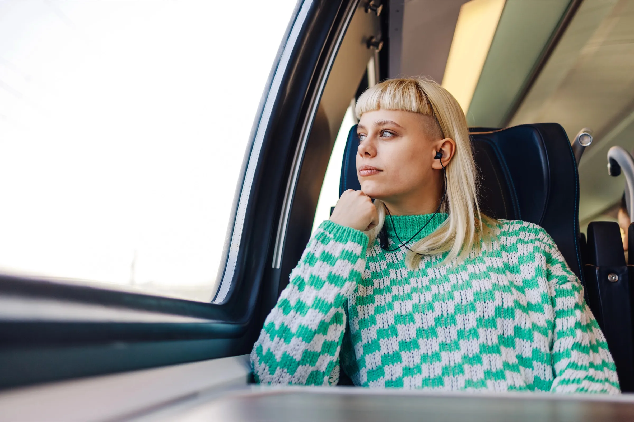 A young woman listening on a train with earbuds